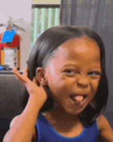 a little girl is making a funny face and sticking out her tongue .