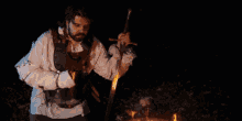 a man with a beard is holding a sword in front of a fire