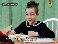 a little girl is sitting at a table with a glass of milk and a piece of paper ..
