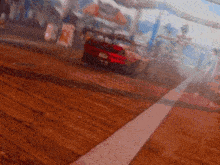 a red car is driving on a dirt road