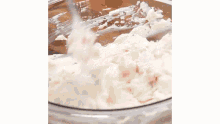 a cup of chocolate chips is being poured into a bowl of frosting .