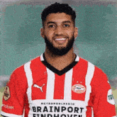 a man with a beard wears a red and white striped shirt that says brainport findhoven
