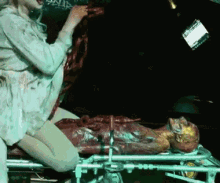 a woman is kneeling over a dead body on a stretcher