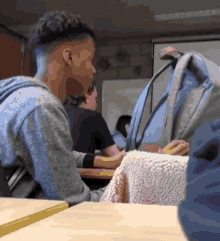 a boy sits at a desk in a classroom with a backpack