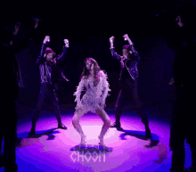 a woman in a feathered dress is surrounded by men
