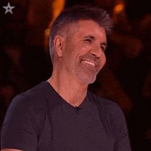 a man with a beard and a black shirt smiles