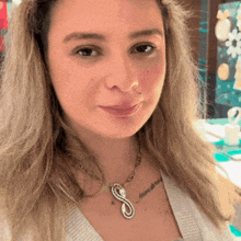 a close up of a woman wearing a necklace with a letter s on it