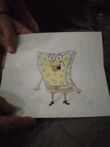 a person holding a drawing of spongebob squarepants on a piece of paper