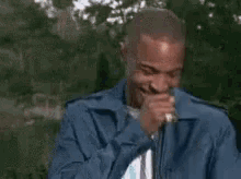 a man in a blue jacket is laughing and crying with emojis .