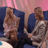 two women are sitting on a blue couch talking