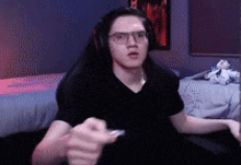 a man wearing headphones and glasses is sitting in front of a computer .