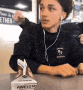 a boy wearing headphones sits at a table with a box of awesome milk