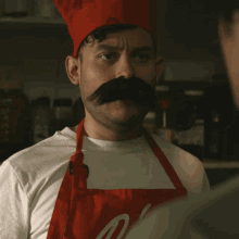 a man wearing a chef 's hat and an apron with the letter n on it
