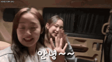two girls are sitting in the back of a car and one of them is waving