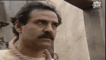 a man with a rope around his neck looks at the camera