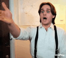 a man wearing suspenders and a white shirt is making a surprised face