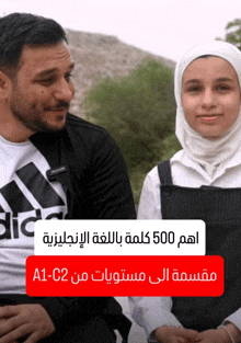 a man wearing an adidas shirt sits next to a girl wearing a white hijab