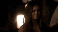 a woman in a dark room smiles at the camera