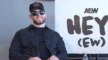 a man sitting in front of a sign that says hey