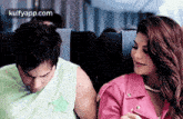 a man and a woman are sitting next to each other on an airplane . the woman is wearing a pink jacket .
