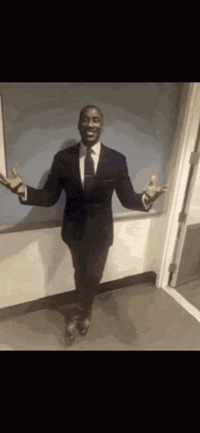 a man in a suit and tie is standing in a doorway with his arms outstretched