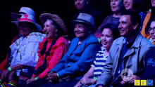 a group of people are sitting in a dark room and smiling for the camera