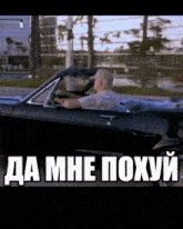 a man is driving a black convertible with the words " da mne poxyui " written on the side