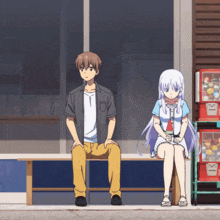 a man and a woman sit on a bench in front of a vending machine