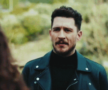 a man with a beard and mustache is wearing a black jacket