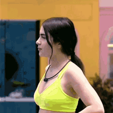 a woman wearing a neon yellow sports bra and a necklace