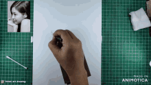 a person is drawing a picture of a girl on a green cutting mat