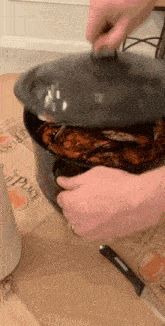 a person is holding the lid of a pot of crabs on a table