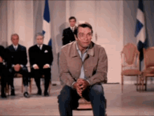 a man is sitting in front of a group of men sitting in chairs