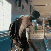 a man walking down an escalator with a backpack