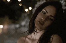a close up of a woman 's face with a blurred background of lights .