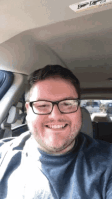 a man wearing glasses is smiling in a car