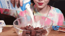 a woman pouring milk into a bowl of cereal