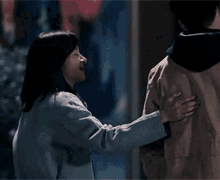 a man and a woman are standing next to each other and the woman is putting her hand on the man 's shoulder