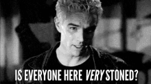 a black and white photo of a man with spiky hair asking is everyone here very stoned .