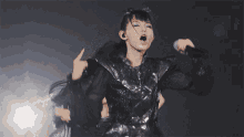 a woman in a metal outfit is holding a microphone and pointing at something