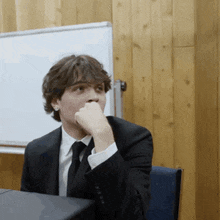 a man in a suit and tie is sitting at a desk