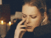 a woman with a nose ring is covering her nose with her hand while sitting in front of candles .