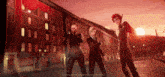 a group of people standing in front of a building with a sunset in the background