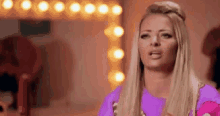 a woman in a pink dress is standing in front of a mirror and making a funny face .