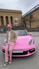 a man standing in front of a pink porsche with a license plate that says yto 673
