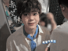 a man wearing a white shirt and a blue scarf has chinese writing on his neck
