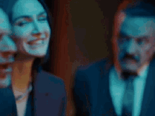 a man in a suit is making a funny face in a dark room while a woman looks on .