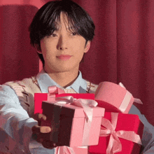a young man is holding a stack of pink presents