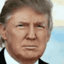 a close up of donald trump 's face in a suit and tie with a serious look on his face .