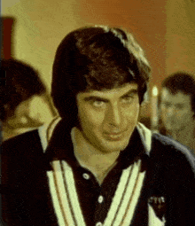 a man wearing a black and white striped sweater is smiling and looking at the camera